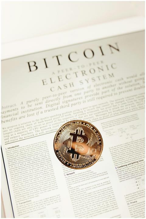 Bitcoin coin placed on a white paper document expl