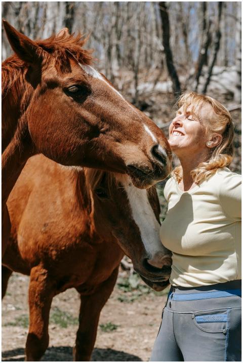A joyful woman interacts with a horse in a sunny o