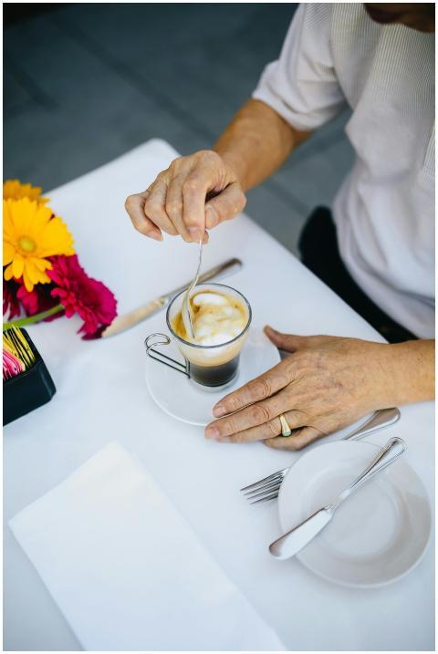 Elderly man stirring cappuccino at an outdoor cafe