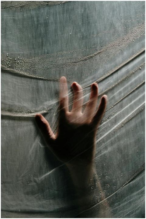 Dramatic hand silhouette pressing against a wet pl