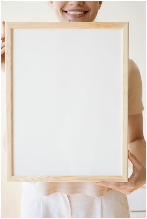 Smiling woman holding a blank framed canvas, perfe