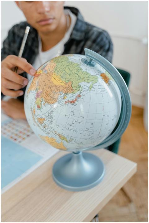 A student pointing at a globe in a classroom setti