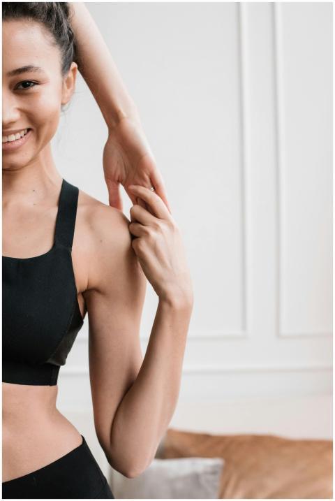 Smiling woman in sportswear stretching indoors, em