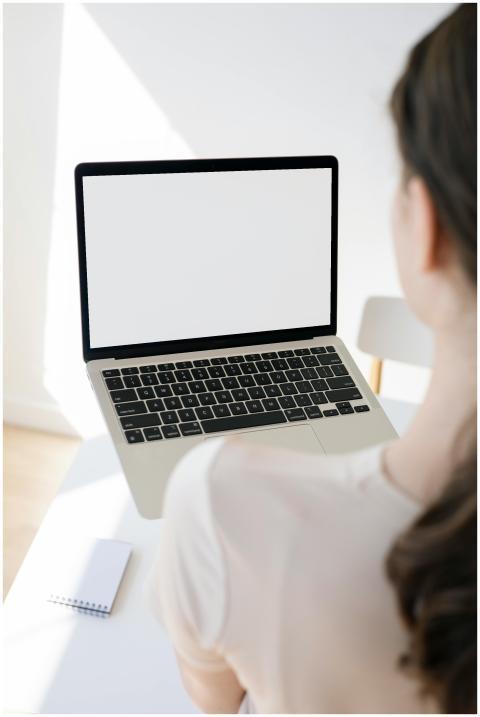 Adult woman in white t-shirt using a blank laptop