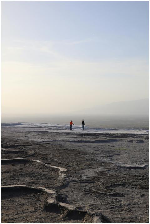 Two individuals walk across the unique barren land