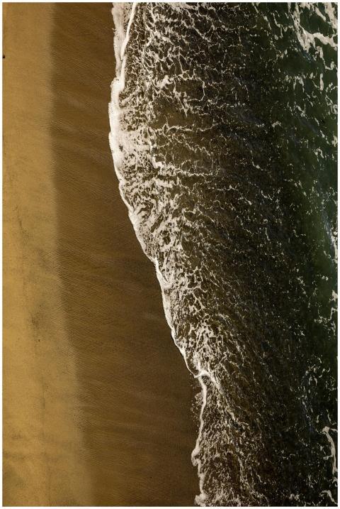 A breathtaking aerial shot of ocean waves gently l