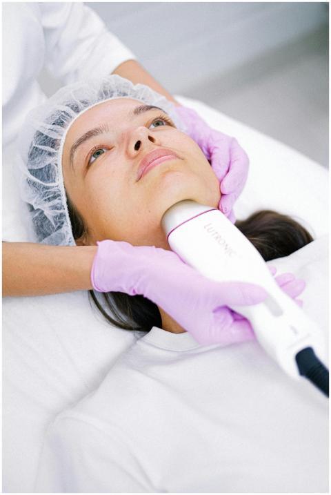 A cosmetologist performs a facial laser treatment
