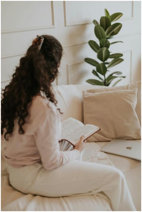 Woman sitting on beige sofa reading a book with a