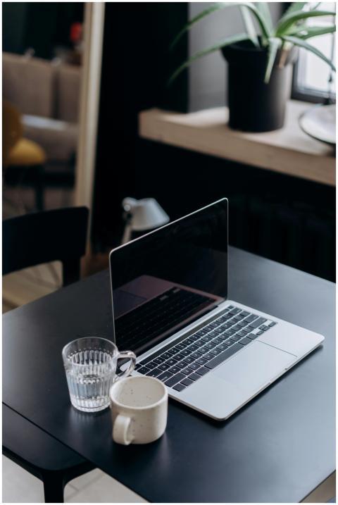 A minimalist workspace featuring a laptop, glass o