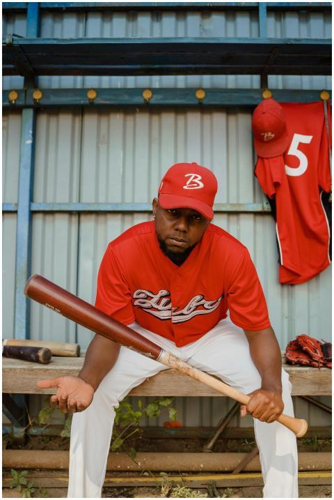 African American baseball player in uniform sittin