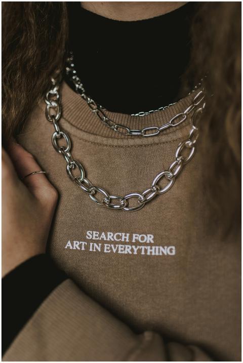 Close-up of a beige sweatshirt with a silver neckl