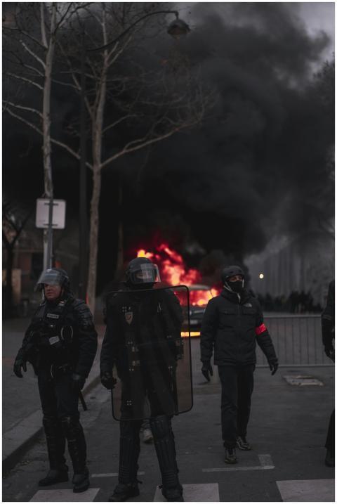 Riot police in gear confronting a street fire duri