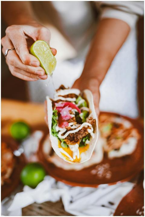A close-up of a taco with lime juice squeezed over