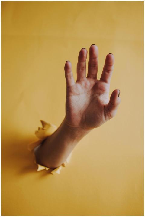 A hand breaks through yellow paper, offering a str