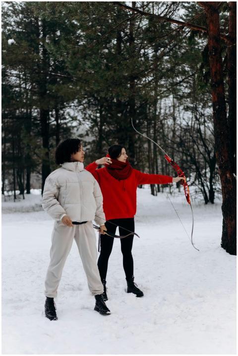 Two individuals practicing archery in a snowy fore