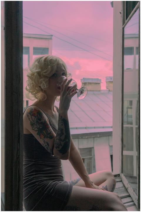Relaxed woman with tattoos enjoying wine by the wi