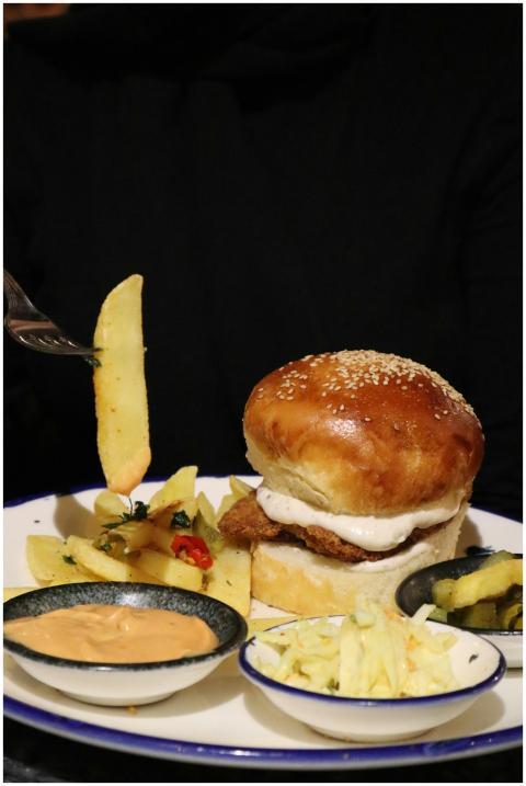 Close-up of a juicy burger with fries and side dis