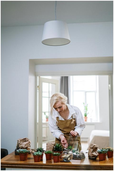 Blonde woman in apron tending succulents in a mode