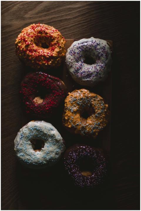 A moody shot of various colorful glazed donuts wit