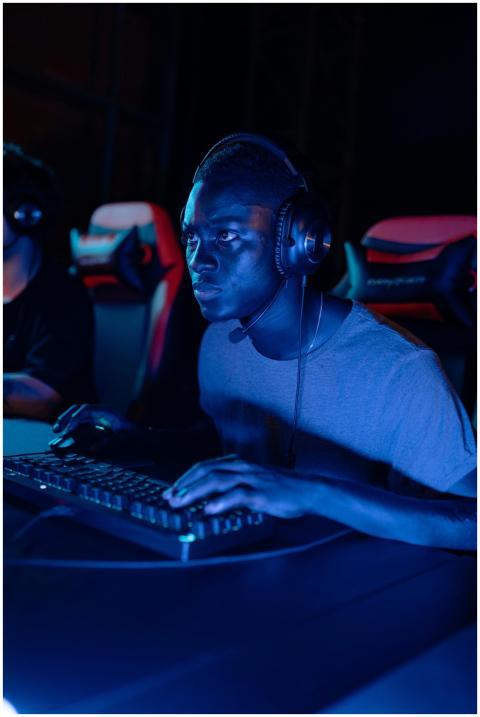 A focused gamer wearing a headset at a computer ga