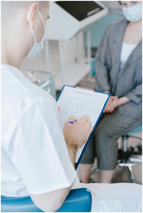 A medical professional takes notes while consultin