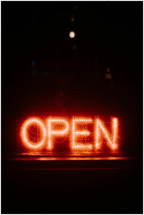 Bright neon open sign glowing against a dark backg