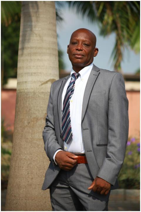 Elegant businessman in suit under palm trees, show