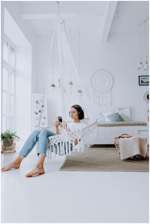 Young woman relaxing in a hammock at home, listeni