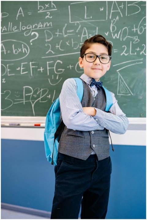 Young boy with glasses standing confidently in fro