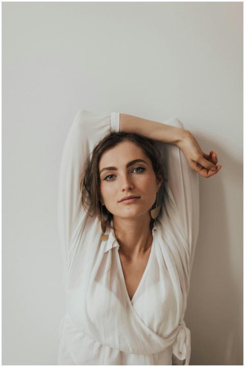 A beautiful woman in a white shirt poses casually