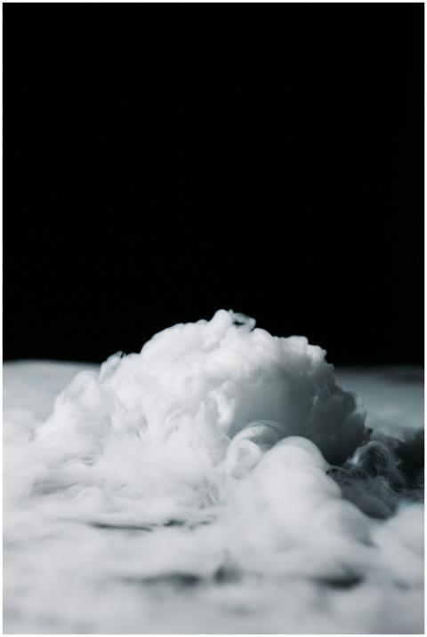 Dynamic cloud of white smoke against a solid black