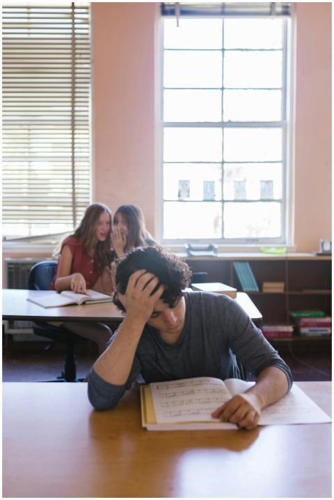 A young man looking stressed while studying in a c