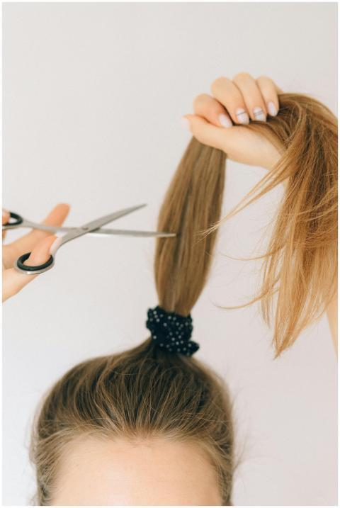 Close-up of scissors cutting long hair indoors, hi