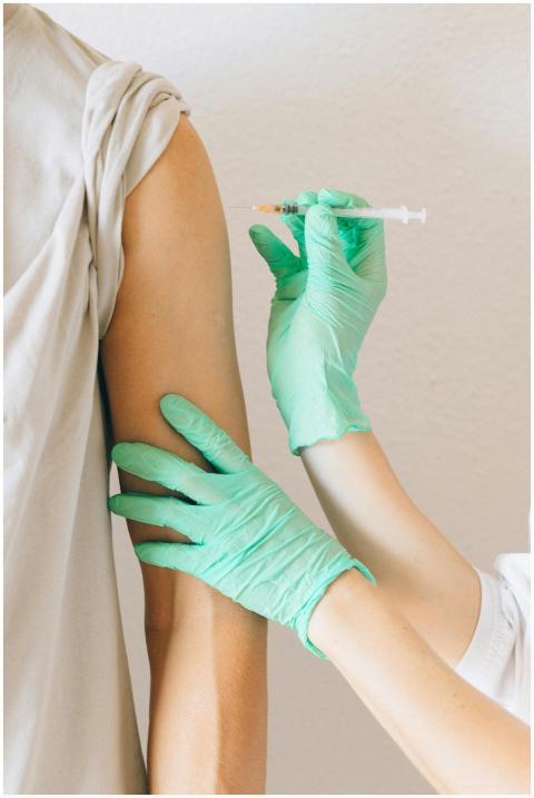 Close-up of gloved hands giving a vaccine injectio