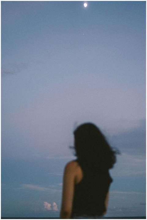 Silhouette of a woman looking at the moon in a ser