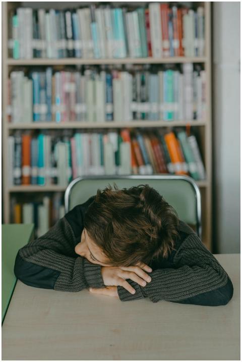 A young boy rests asleep with his head on a desk i