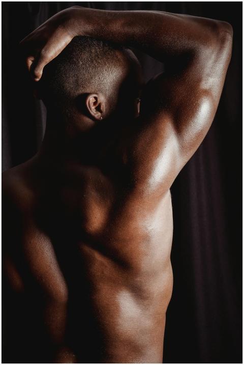 A shirtless muscular black man flexing his arm, sh