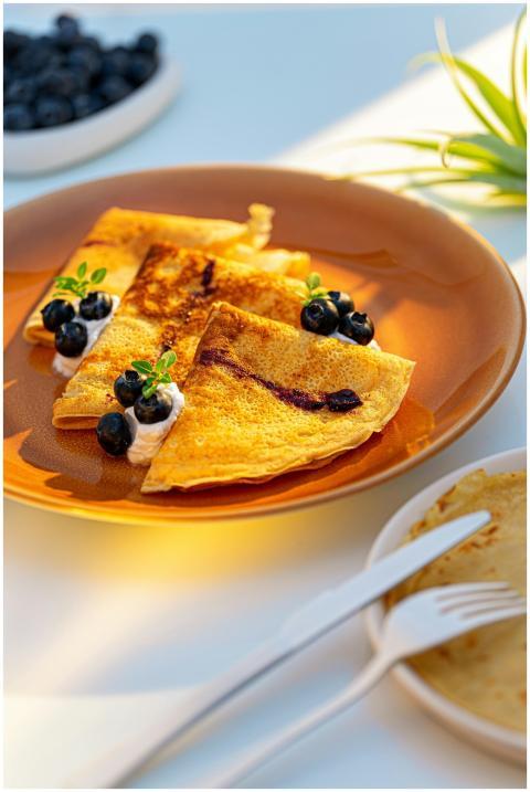 Golden crepes with fresh blueberries and cream on