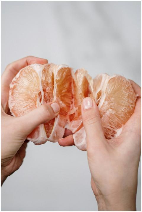 Two hands gently holding a peeled grapefruit slice