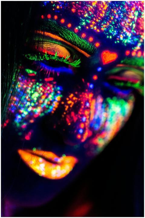 Close-up of a woman's face painted in neon colors
