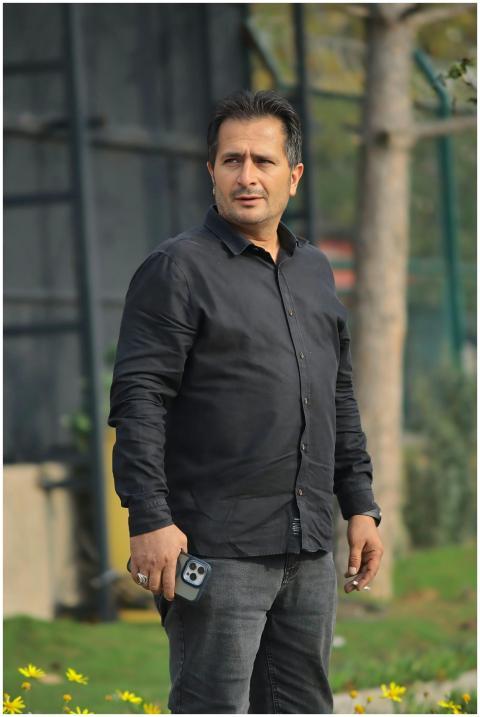 Man in a black shirt holding a smartphone outdoors