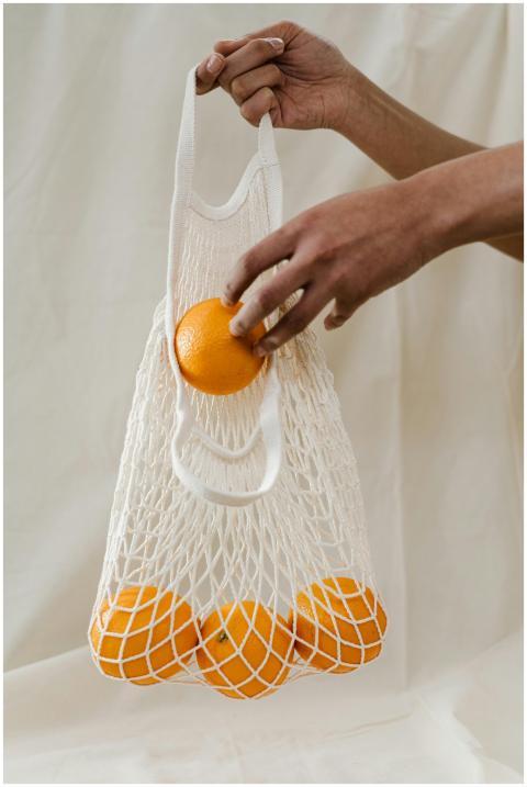 Hand holding a reusable mesh bag filled with fresh