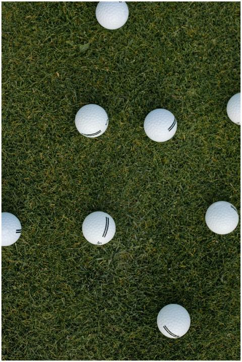 Scattered golf balls on lush green grass viewed fr