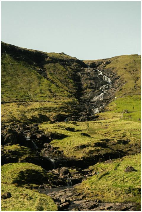 Serene waterfall cascading down lush green hills u
