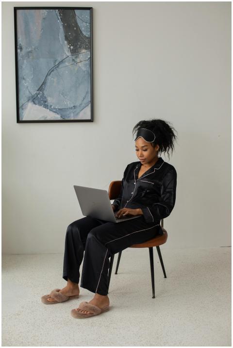 African American woman in pajamas using laptop, se