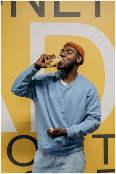 Casual man in blue sweatshirt drinking healthy jui