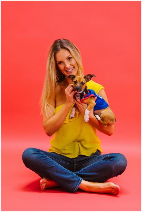 Cheerful woman in bright yellow top holding a chih