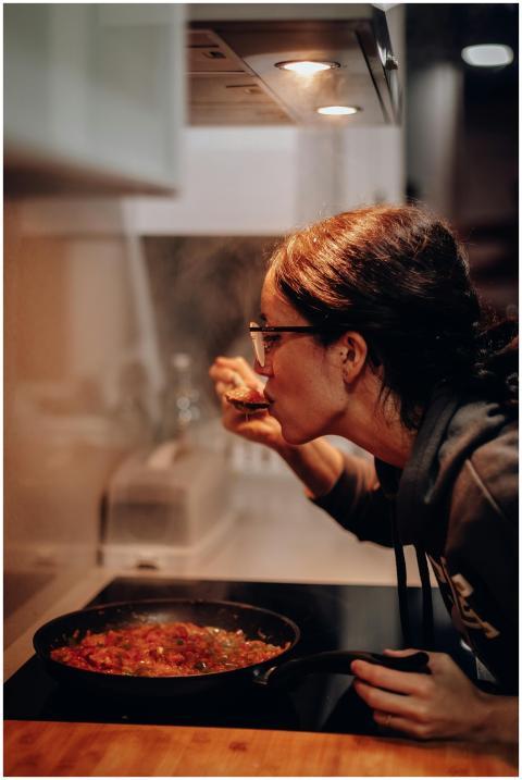 Woman cooking and tasting a dish on the stove, sho