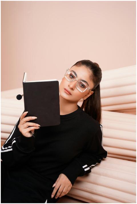 A young woman in sportswear and eyeglasses reads a