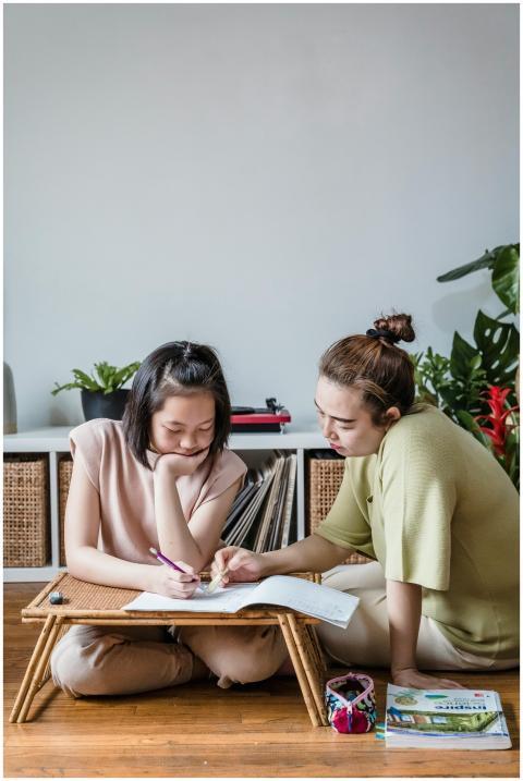 A mother helps her daughter with homework, fosteri